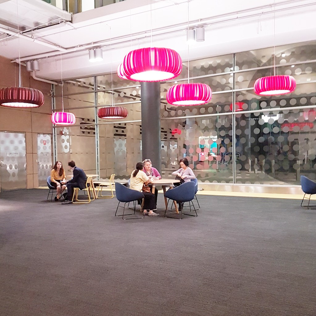 People sit at tables inside the ABC Sydney building, waiting for filming to start