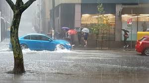 Blue car stuck in floodwater on a commercial street