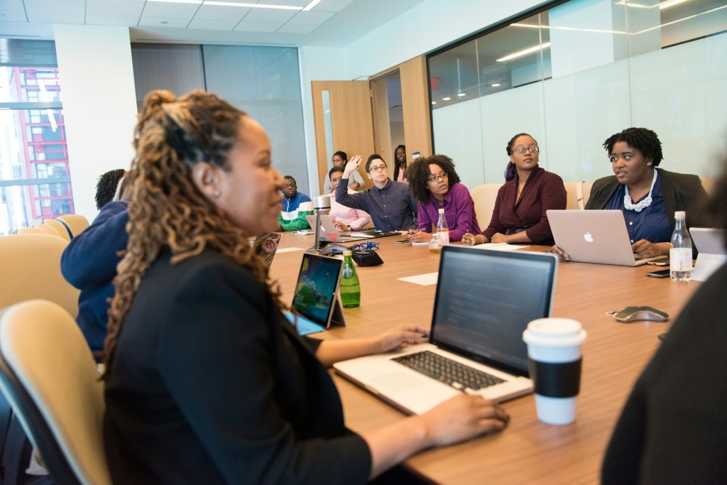 People sit around a boardroom in front of their laptops
