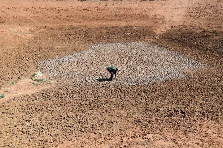 Aerial view of a man crouching surrounded  by dry, barren land