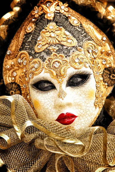 Person wearing a golden masks with crystals and leafing, and a golden tulle collar