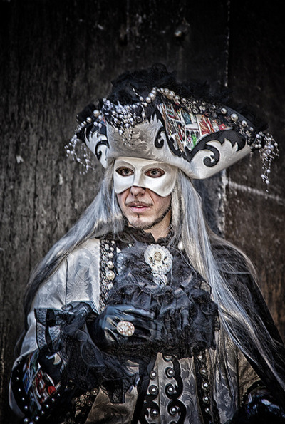Man wearing a silver mask and costume, with long silver hair, and an ornate pirate hat