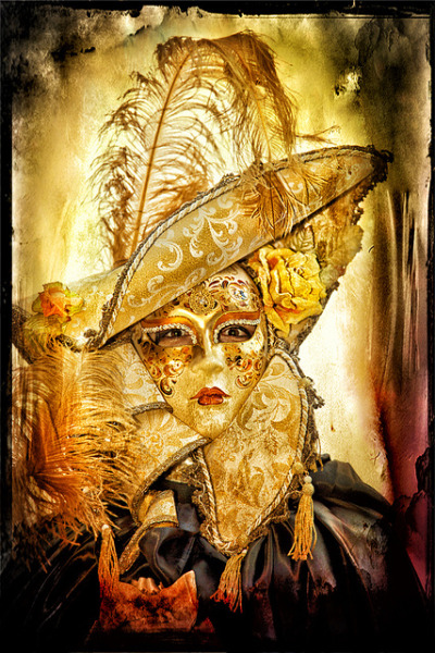 Woman wearing a golden mask and costume, with a pirate hat and long golden feather and collar with tassels