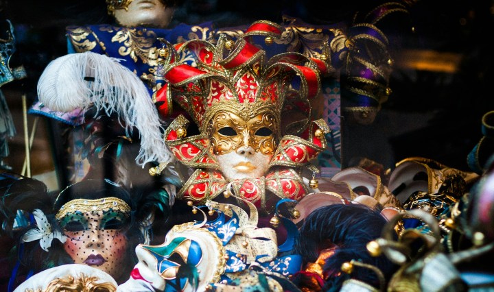 A groups of masks, with a red and golden jester's mask in the centre