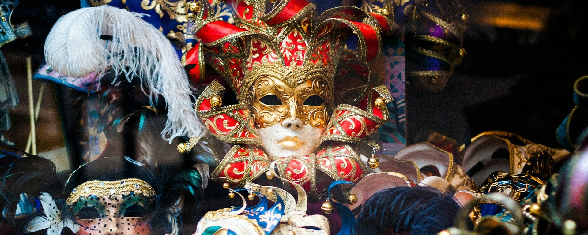 A groups of masks, with a red and golden jester's mask in the centre