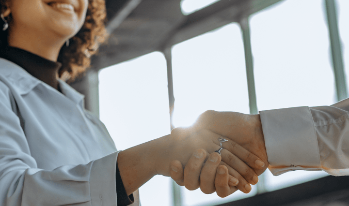 A Black woman shakes hands with a white man