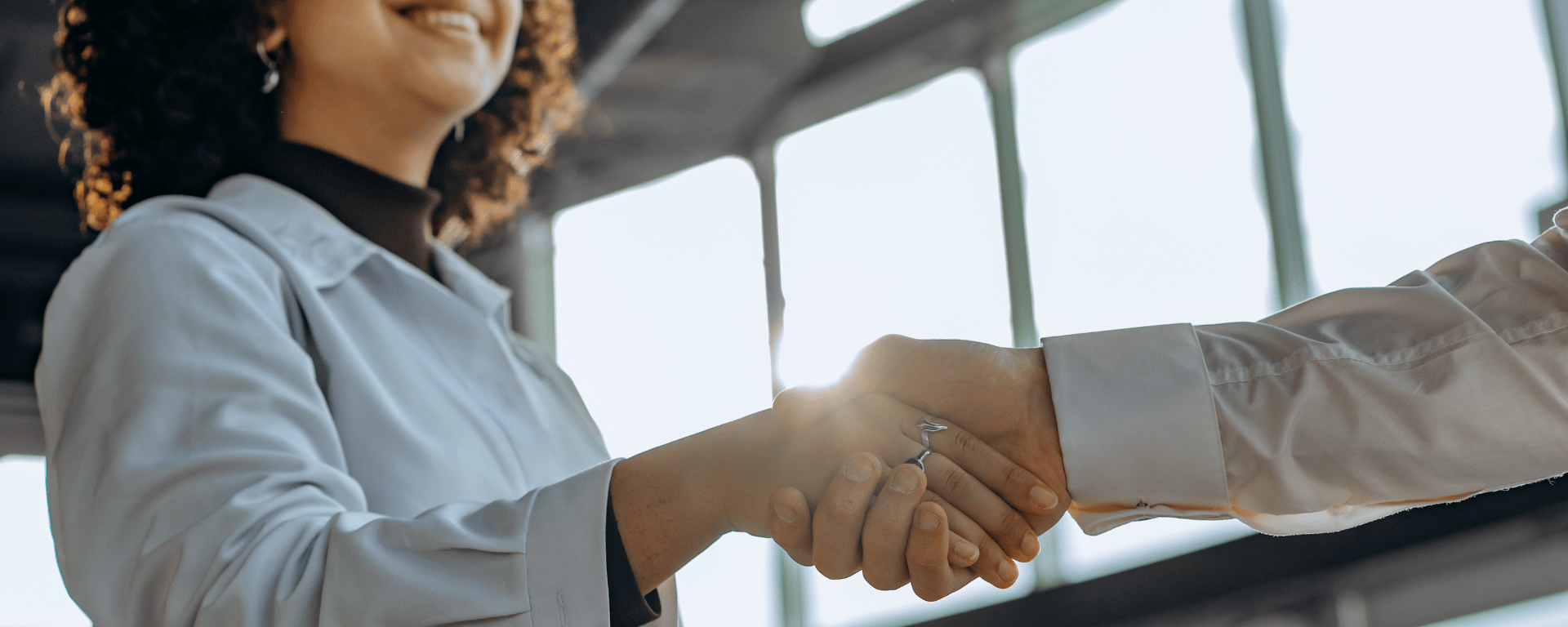 A Black woman shakes hands with a white man