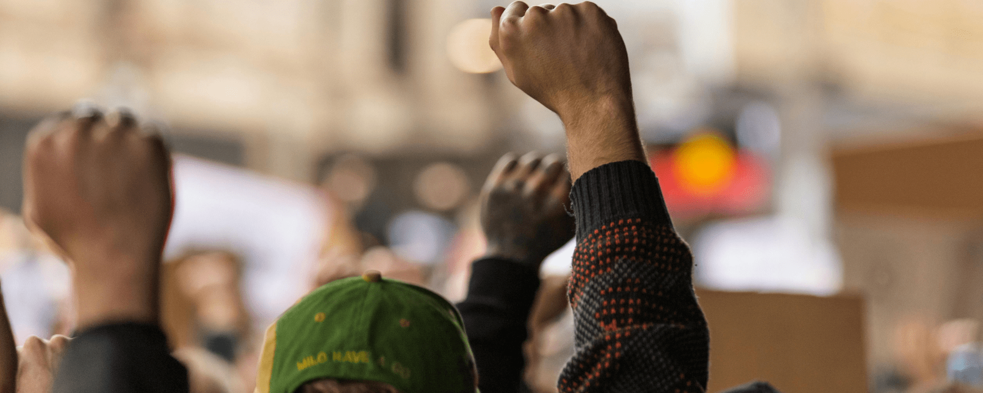 People of colour workers raise their fists in the air during a protest