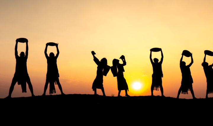 Vietnamese dancers silhouetted against the sunset. They hold up instruments and pose in triumph and celebration